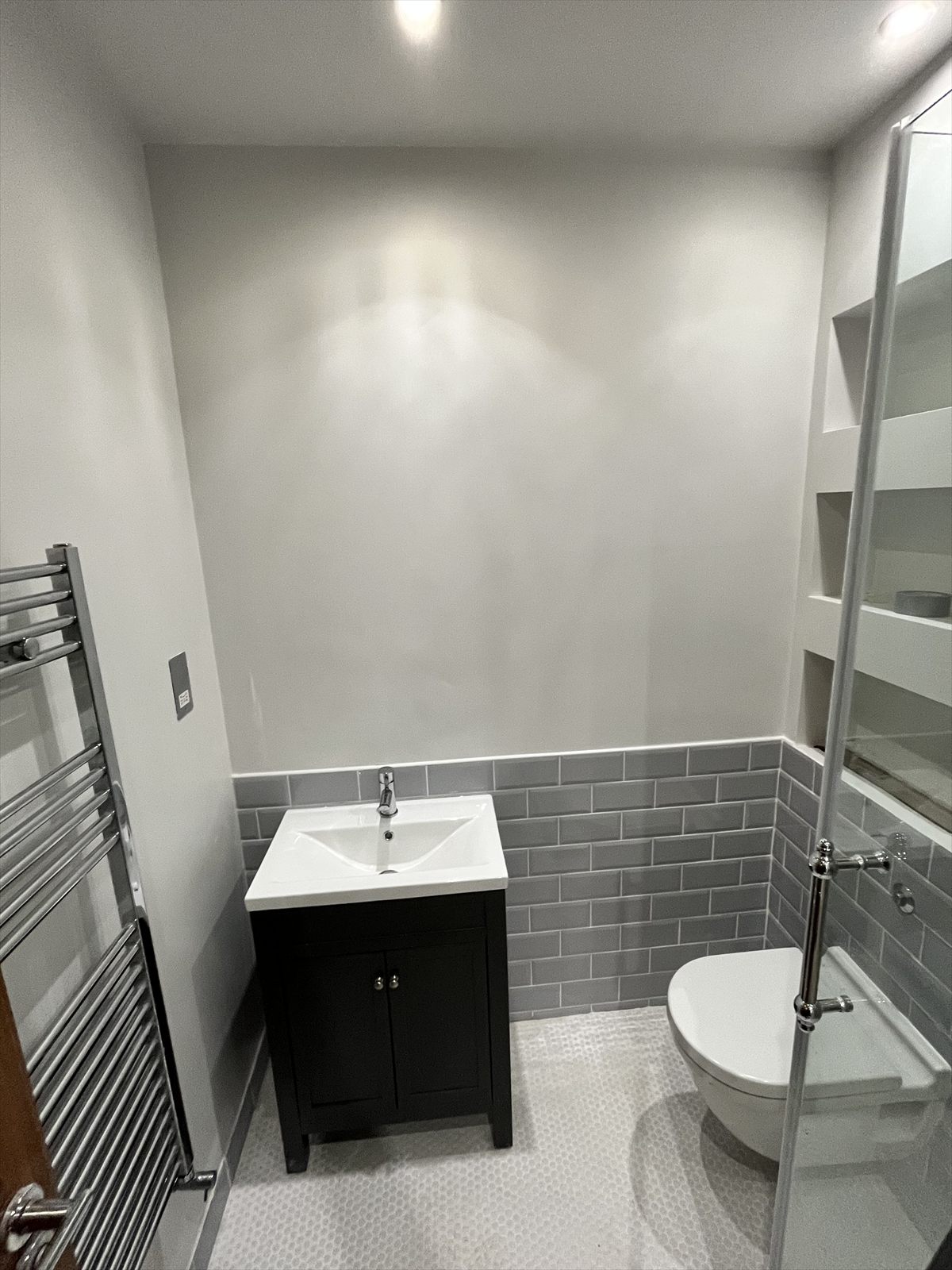 Finished ensuite bathroom with grey metro tiles, a vanity unit and a chrome heated towel rail