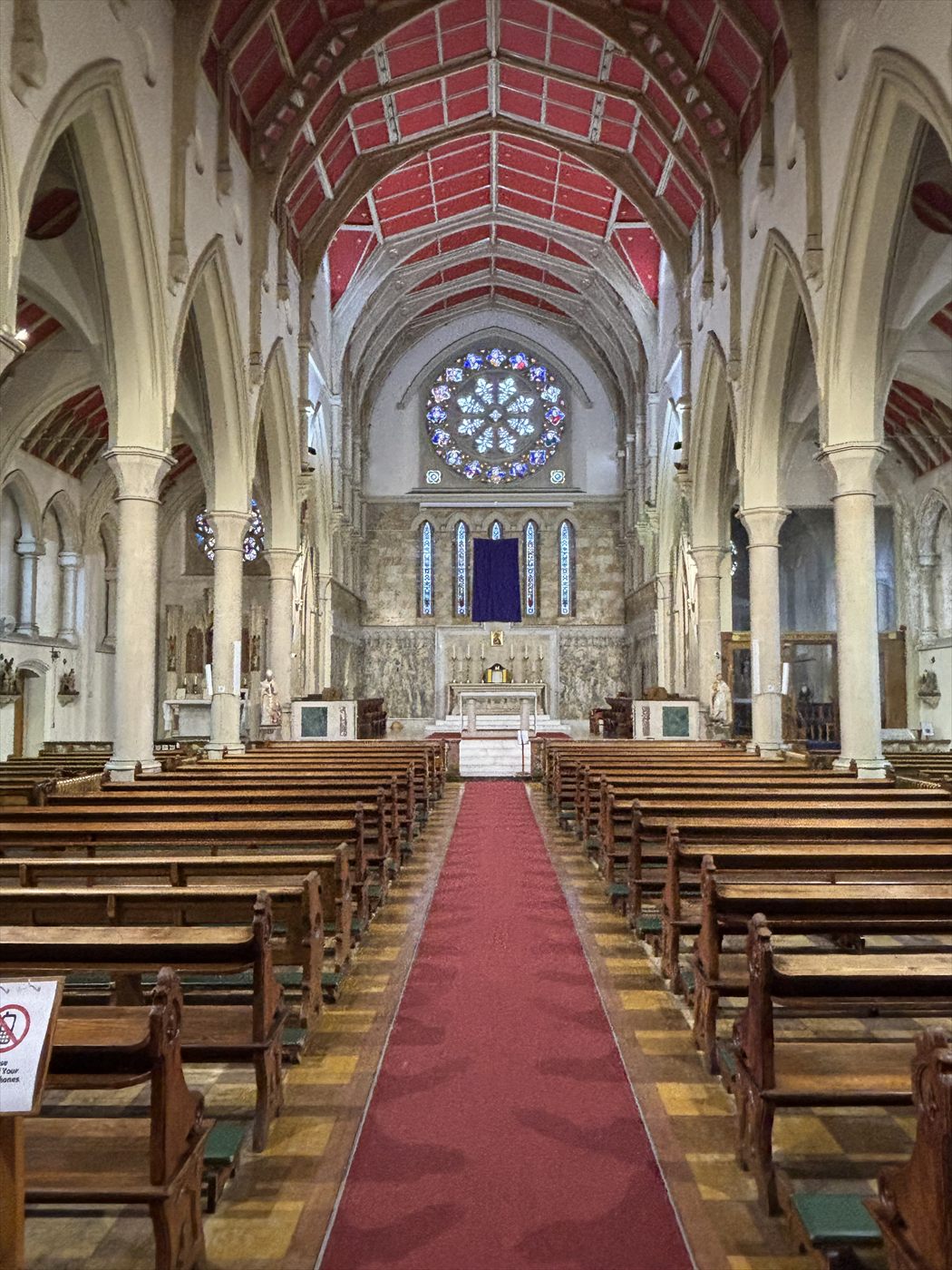 Church nave lit only by daylight through the rose window, before the new lighting was installed