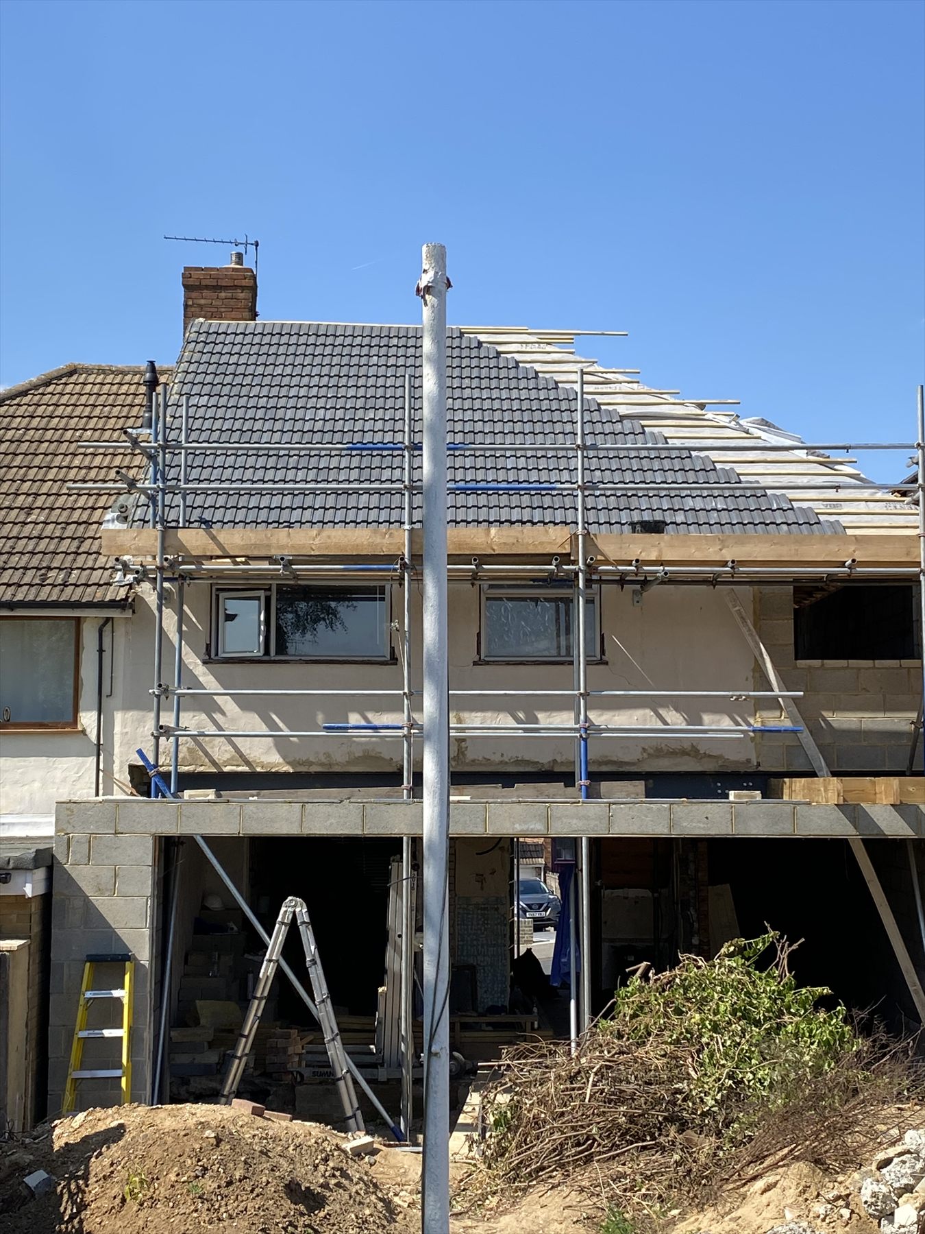 A large rear extension nearing completion, scaffolded with tiled roof and rendered walls