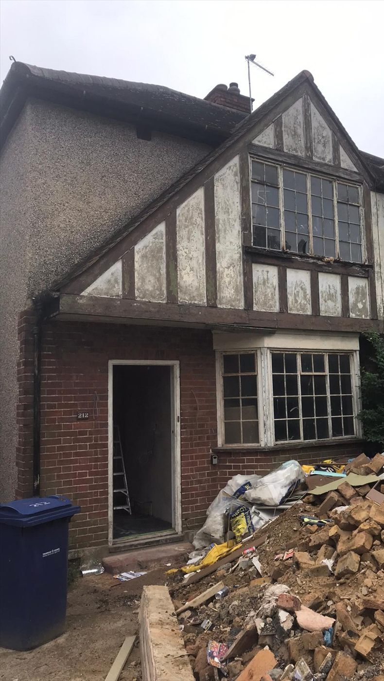 The house stripped back before the extension, with the old timber gable exposed and a pile of rubble by the front door