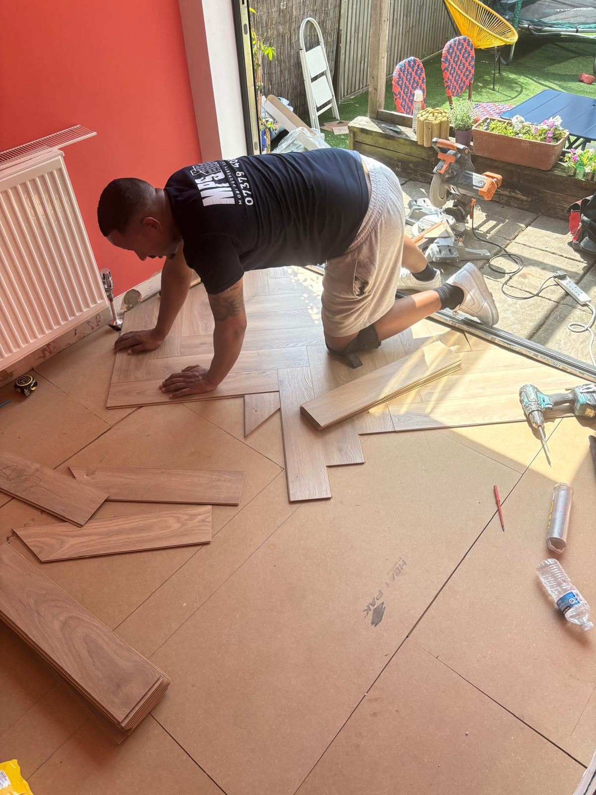 Fitter laying herringbone flooring on site wearing an MPS branded shirt