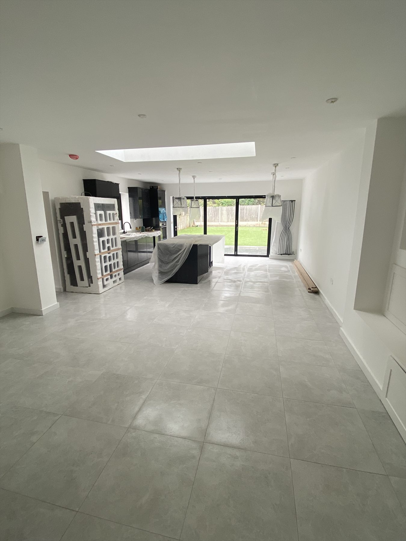 Large open-plan kitchen and dining extension nearing completion, with a roof lantern and bifold doors to the garden