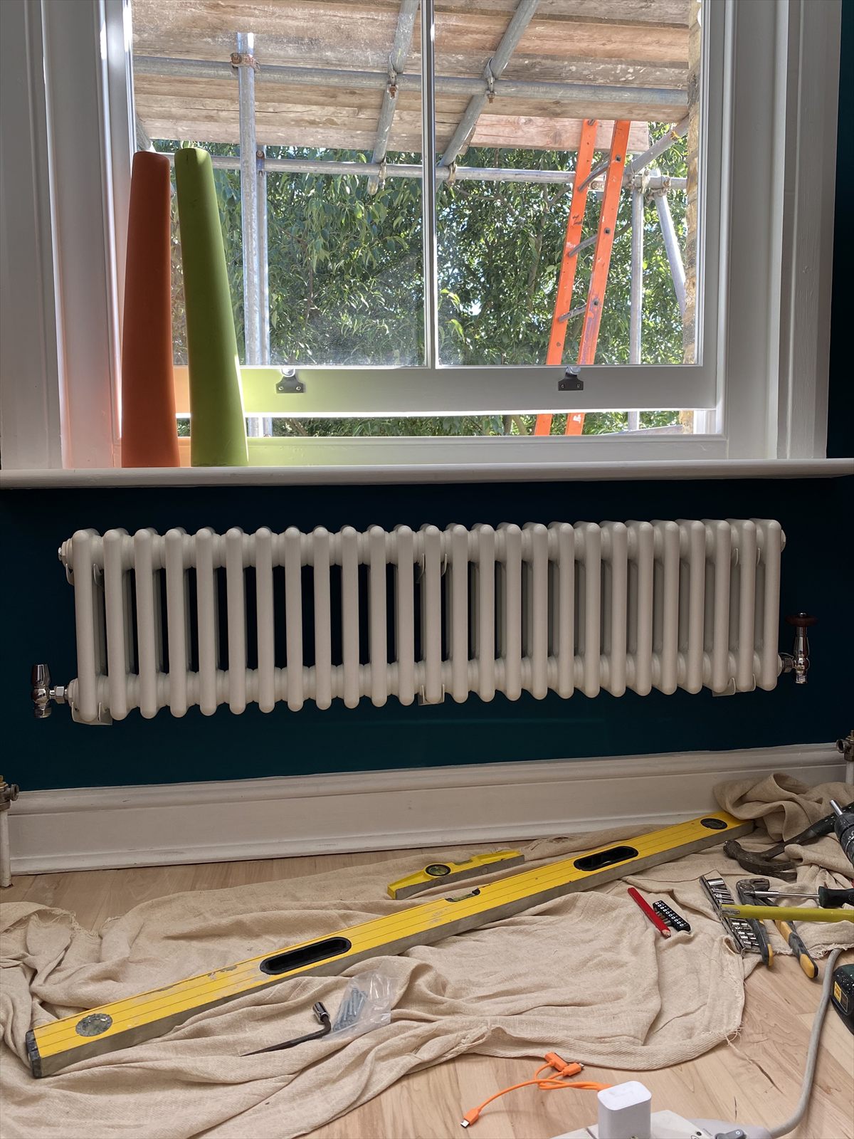 Newly installed column radiator on a decorated wall, with tools laid out for the final fix