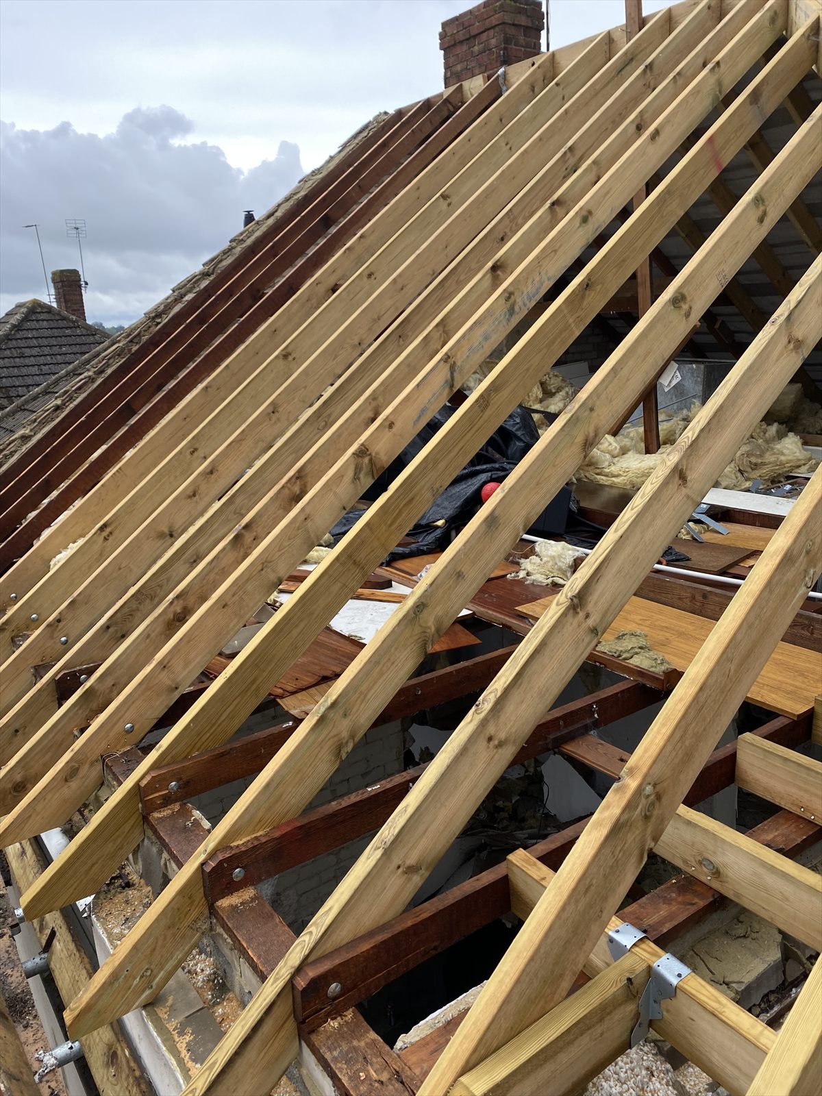 View along a stripped roof structure showing new rafters and insulation between them