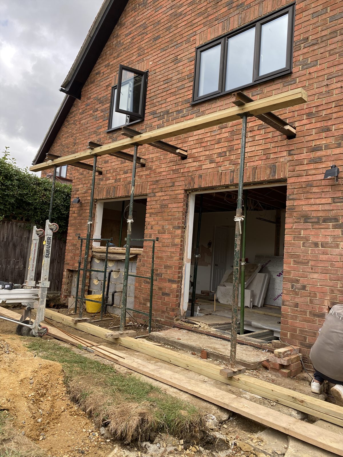 New window and door openings formed in a brick rear elevation, supported on scaffold towers